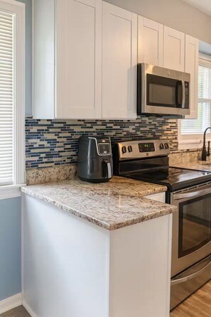 A kitchen with white cabinets, a stainless steel microwave, a coffee maker, and a tiled backsplash. - Executive 4BR Home Fully Furnished. CALL IT HOME 30+Day (Louisville)