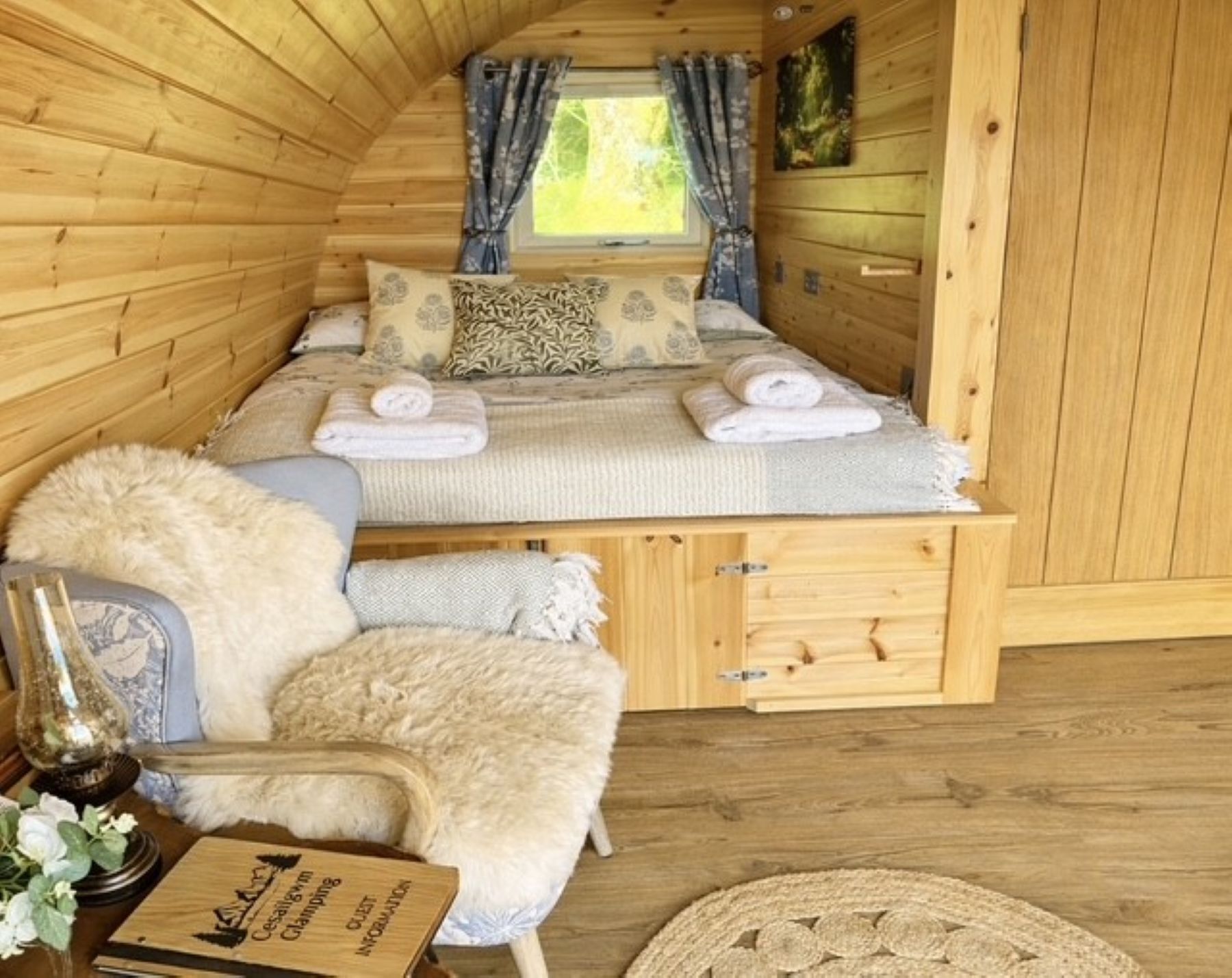 Ein gemütliches Blockhauszimmer mit Bett, Stuhl, kleinem Tisch und Fenster.