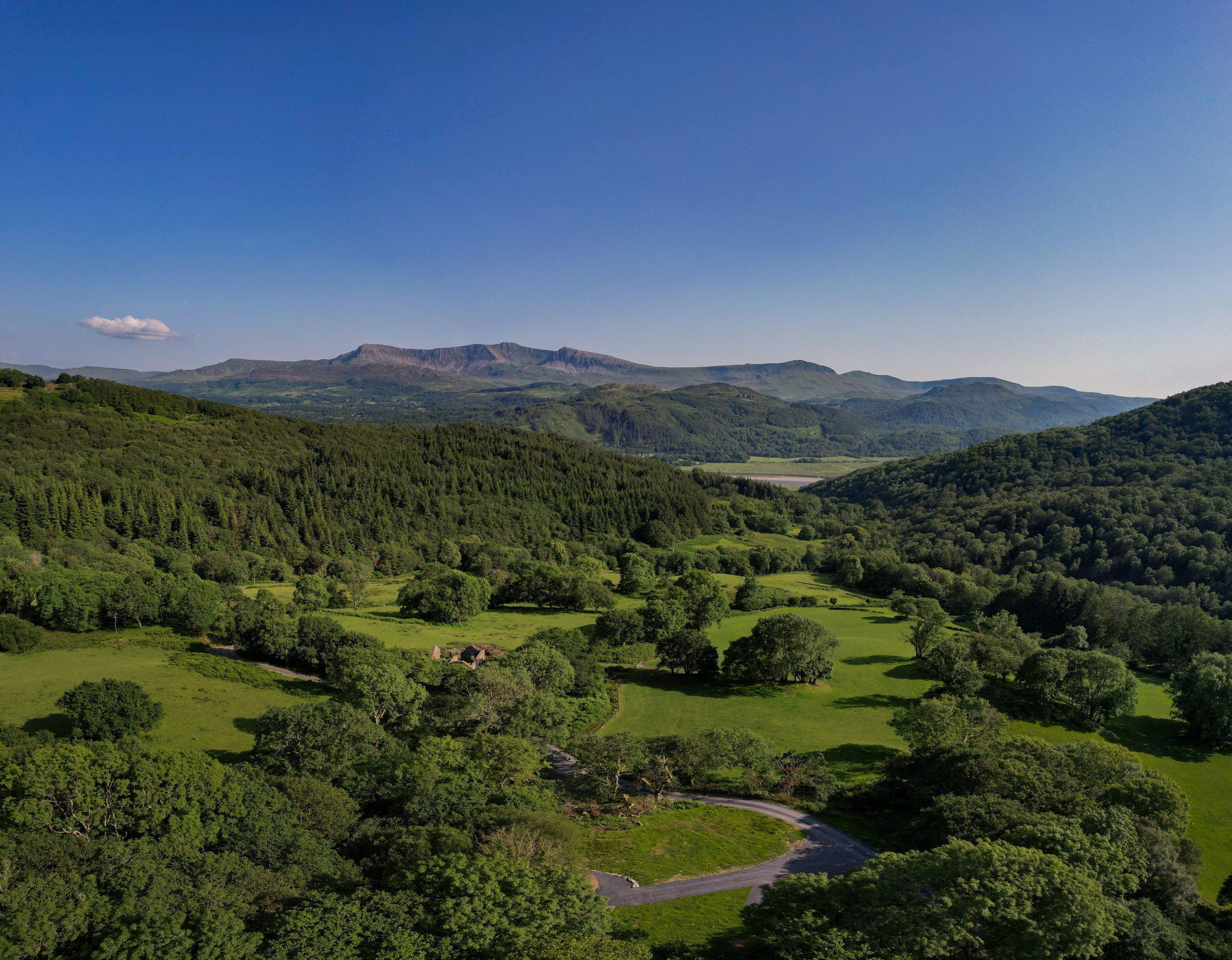A mountainous landscape with dense forests and a winding road.