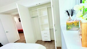Een slaapkamer met een bed, een witte inbouwkast en een raam met een plant.