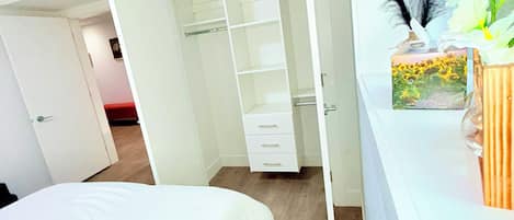 Un dormitorio con cama, un armario blanco y una ventana con una planta.