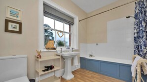 Ein Badezimmer mit Toilette, Waschbecken, Badewanne und einem Fenster mit Blick auf Bäume.