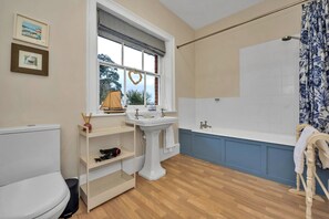 Ein Badezimmer mit Toilette, Waschbecken, Badewanne und einem Fenster mit Blick auf Bäume.