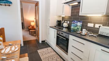 Una cuina moderna amb armaris blancs, tauleig negre i salabost a la paret.