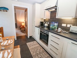 Une cuisine moderne avec des meubles blancs, un plan de travail noir et un pare-feu en carrelage.
