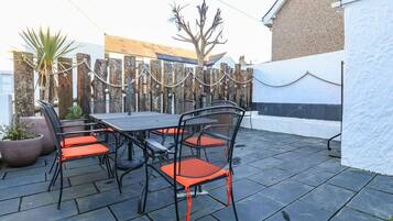 Un patio al aire libre con una mesa y sillas, rodeado por una valla de madera.