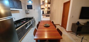 A compact kitchen with a stove, washing machine, and a dining table with chairs. - Cozy 1-bedroom apartment in pleasant Maceió with AC and gym (Maceió)