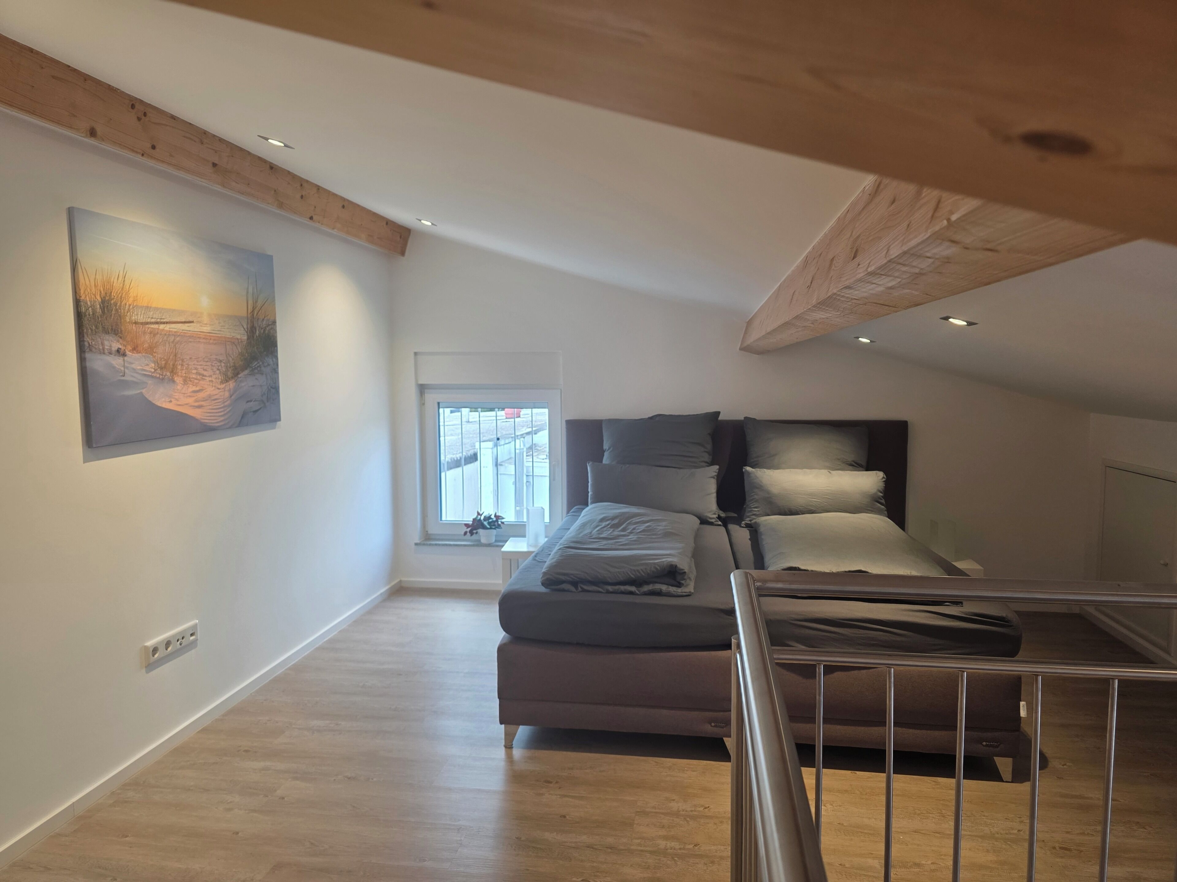 Ein Schlafzimmer mit einem Bett, einem Fenster und einem Bild an der Wand.