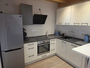 A modern kitchen with a built-in oven, a coffee machine, and a kettle.