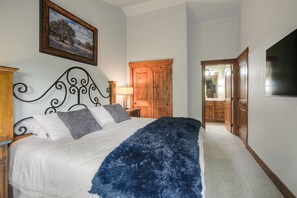 A bedroom with a bed, a wooden door, a mirror, and a painting on the wall.