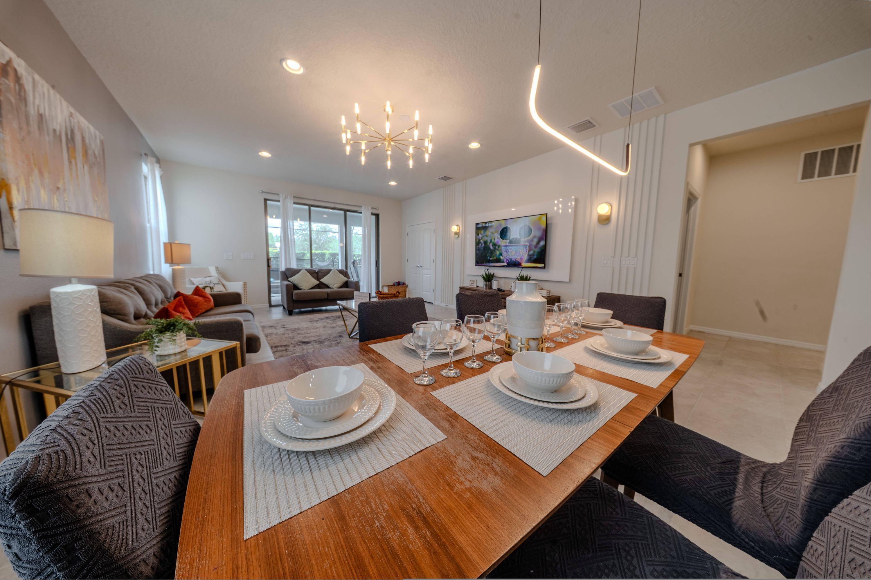 A modern dining area with a wooden table set for six, surrounded by patterned chairs.