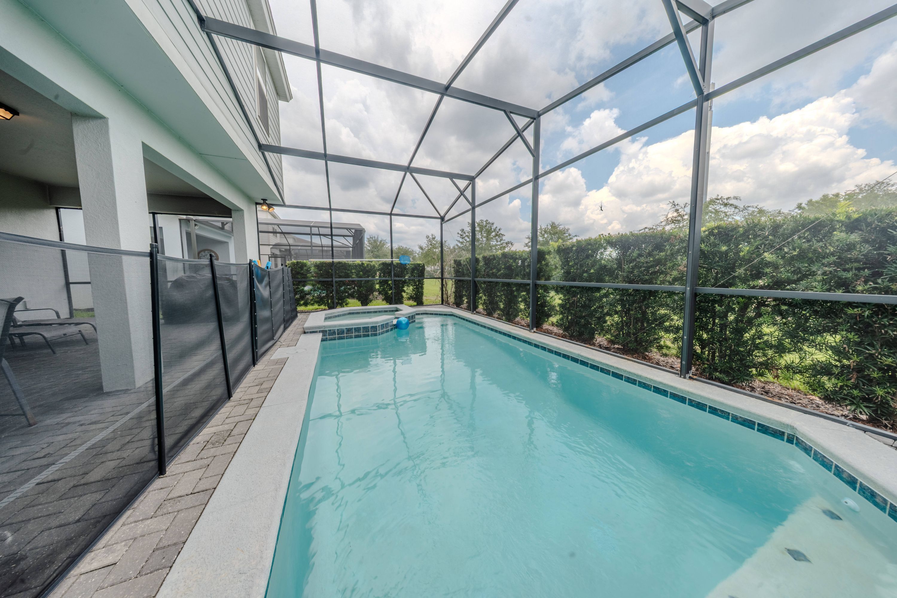 A rectangular pool with a clear blue water surface, surrounded by a metal fence and a glass enclosure.