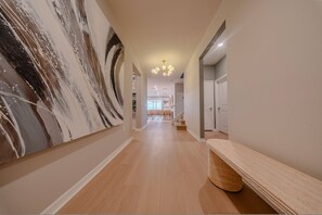 Un couloir avec un mur en marbre, un plancher en bois, un banc et un escalier menant à une autre pièce.