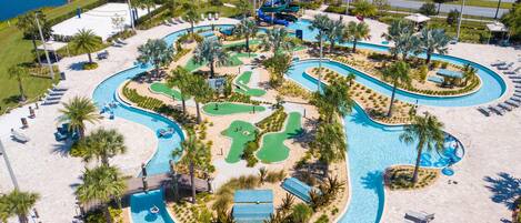 An aerial view of a resort with a large pool area, multiple water slides, and a basketball court.