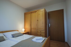 A bedroom with a bed, a nightstand, a lamp, and a wardrobe.