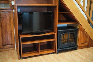 Eine Holzunterhaltungseinheit mit einem Fernseher und einem schwarzen Kaminofen.