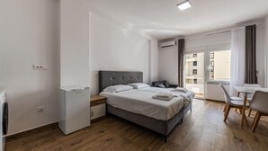 Een moderne hotelkamer met een bed, nachtkastje en een klein bureau met stoel.