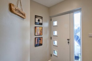 A hallway with a wooden sign, three framed pictures, and a door with multiple windows. - Cozy House Near Whitby Harbour (Bude)