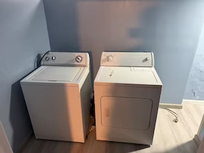 Zwei übereinander gestapelte Frontlader-Waschmaschinen in einer Ecke mit Holzboden und schlichter Wand.