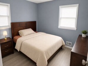 A bedroom with a bed, bedside tables, a lamp, a potted plant, and a dresser. - Spacious 5BR Home for Families, Crews & Nurses 30+Day (Louisville)