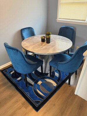 A round dining table with six blue chairs, a blue patterned rug, and a small potted plant on the table. - Spacious 5BR Home for Families, Crews & Nurses 30+Day (Louisville)