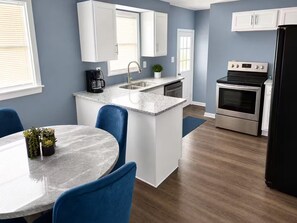 A modern kitchen with white cabinets, a stainless steel oven, and a black refrigerator.