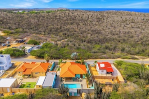 A coastal residential area with houses, a swimming pool, and a view of the sea. - 5BR Villa w/ Private Pool & Palapa, Noord Aruba (Noord)