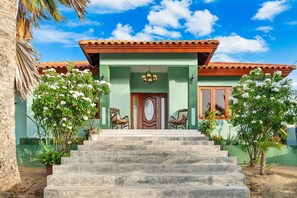 A two-story house with a red-tiled roof, a central door, and a staircase leading to the entrance. - 5BR Villa w/ Private Pool & Palapa, Noord Aruba (Noord)