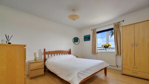 Ein Schlafzimmer mit einem hölzernen Bett, einem Nachttisch, einem Kleiderschrank und einem Fenster mit Blick.