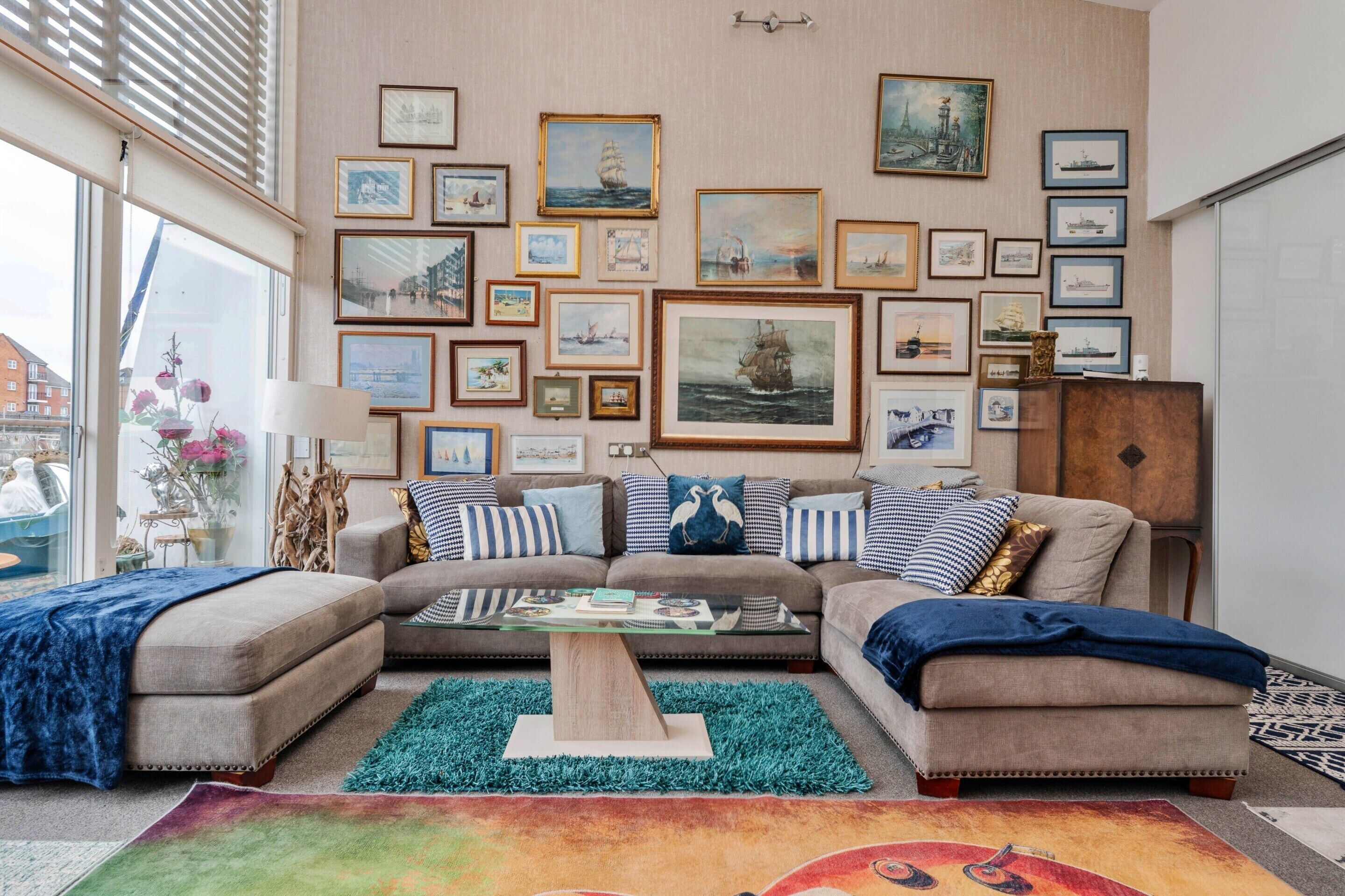 Un salón con un conjunto de sofás, una mesa de centro y una pared decorada con pinturas marinas enmarcadas.