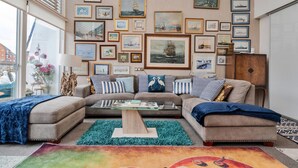 Un salón con un conjunto de sofás, una mesa de centro y una pared decorada con pinturas marinas enmarcadas.