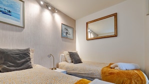 Habitación de hotel con dos camas, una mesita de noche, una lámpara y un espejo.