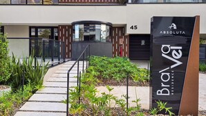 Entrada de un edificio moderno con fachada de vidrio, un letrero que dice 'Brava Residence' y el número '45' indicando la dirección.