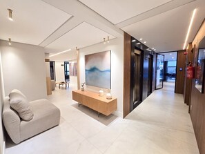 Um lobby de hotel moderno com uma receção, área de estar e uma grande pintura abstrata.