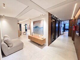 Um lobby de hotel moderno com uma receção, área de estar e uma grande pintura abstrata.