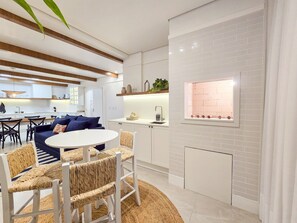 A modern kitchen with white cabinetry, a built-in brick backsplash, and a window with a view. - Bravavel na Praia Brava by LikeHome (Balneário Camboriú)