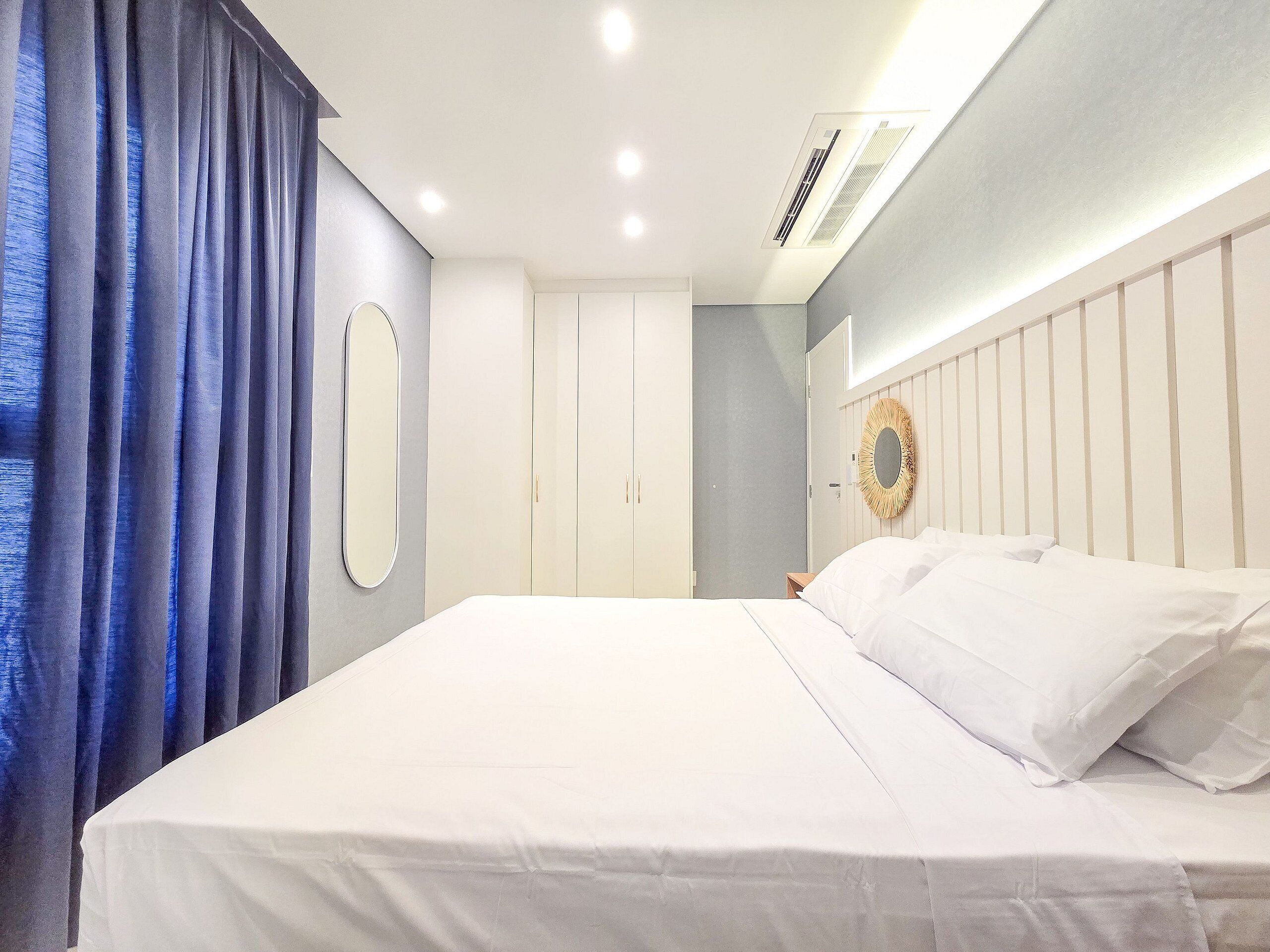 Ein Schlafzimmer mit einem Bett, einem Kleiderschrank, einem Spiegel und einer Deckenleuchte.