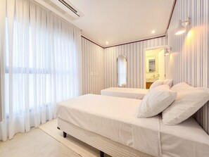A hotel room with a large bed, a mirror, and a window with curtains.