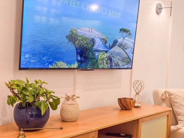 A television mounted on a wall displaying a scenic landscape. - Bravavel na Praia Brava by LikeHome (Balneário Camboriú)