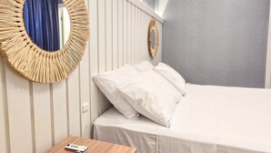 Ett hotellrum med en säng, ett sängbord och två speglar som är monterade på väggen.