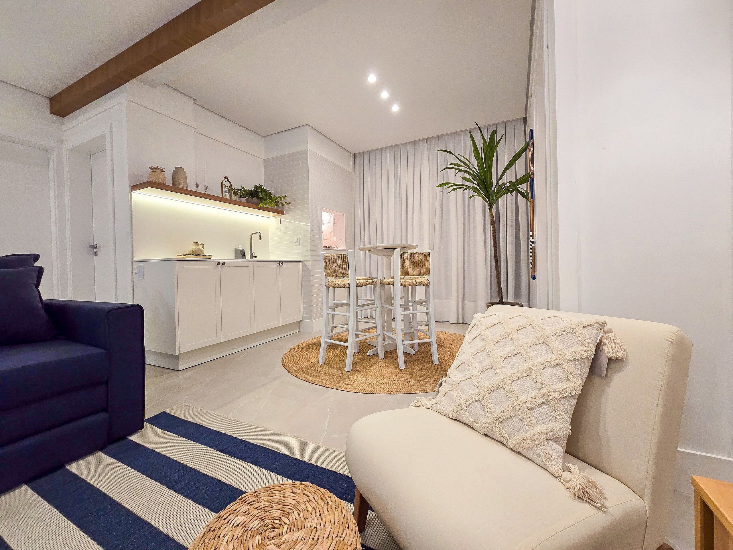 A modern living room with a sofa, a chair, a kitchen area, and a dining table.