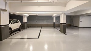 Un estacionamiento con paredes blancas, pilares de concreto y un coche blanco estacionado en una de las bahías.
