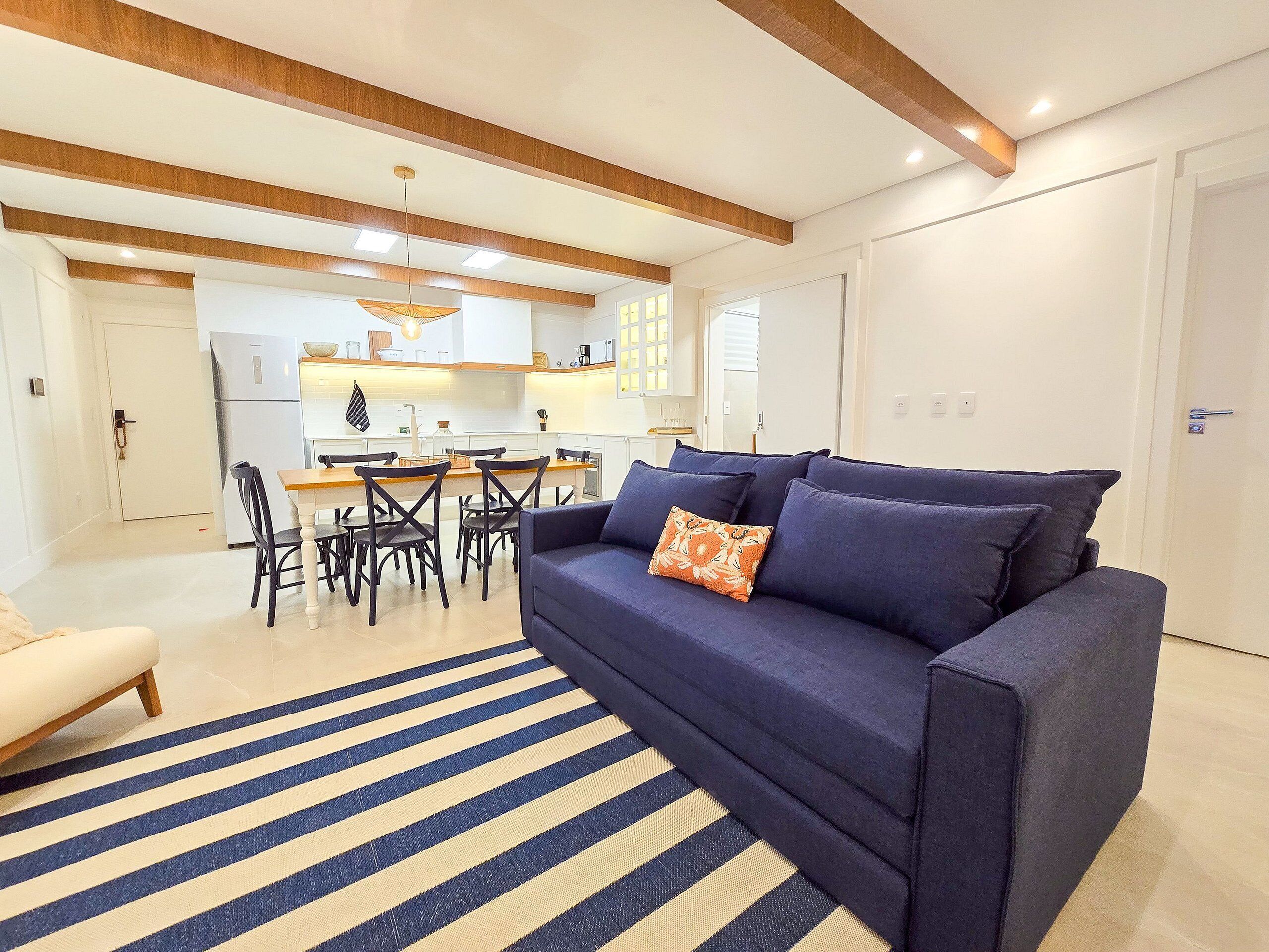 A modern living room with a sofa, a striped rug, and a dining area with chairs and a table.
