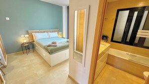 A bedroom with a bed, bedside table, and a mirror. - Luxury apartment with pool views from a large terrace on world class golf resort (MC)