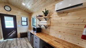 Una cocina con paredes de madera, un reloj, un aire acondicionado y una ventana.