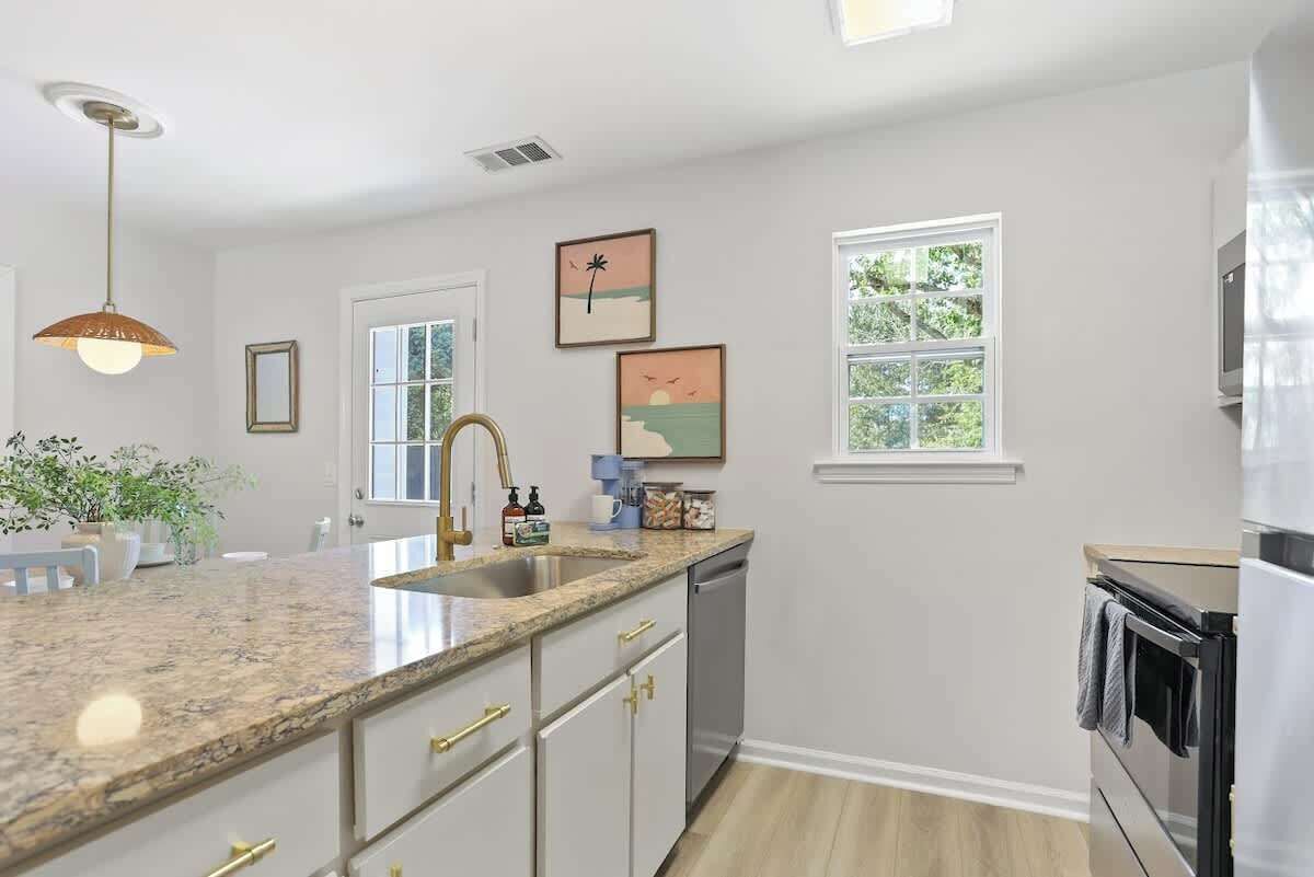 A kitchen with a granite countertop, stainless steel appliances, and a window with a view of greenery.