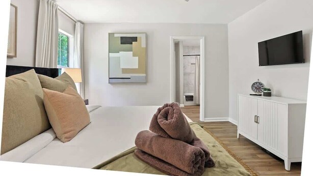 Ein Hotelzimmer mit Bett, Fernseher, einem Gemälde und Blick ins Freie.