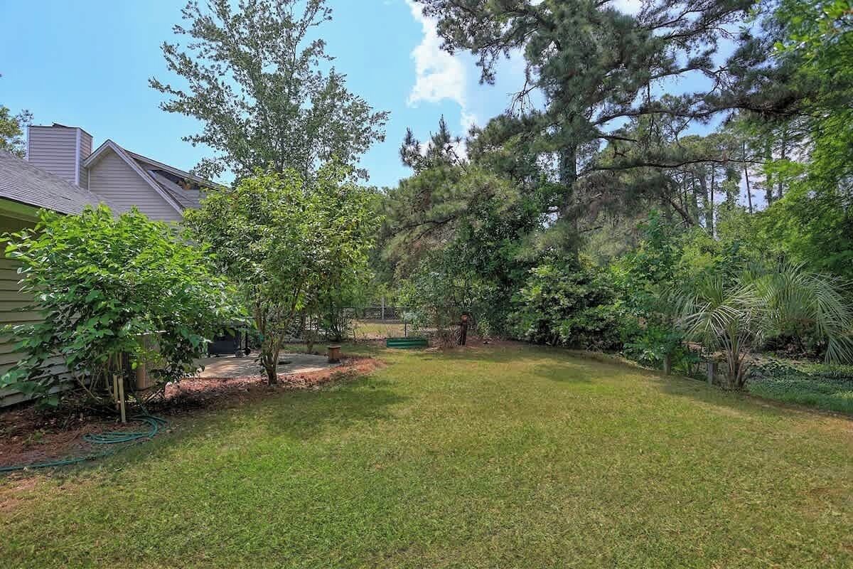 A residential backyard with a lawn, trees, and a house.