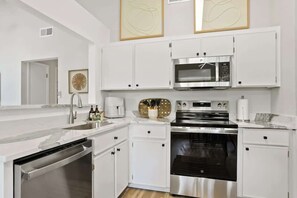 Una cocina moderna con armarios blancos, electrodomésticos de acero inoxidable y encimera de mármol.
