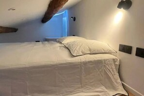 A bedroom with a bed, a wall-mounted light, and a window with a blue tint. - Aix-en-Provence, Air-Conditioned Apartment with a Terrace (Aix-en-Provence)